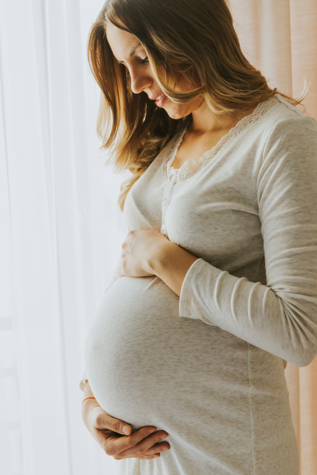 Pregnant woman holding her belly, representing prenatal chiropractic care on the home page of Skelly Chiropractic and Wellness