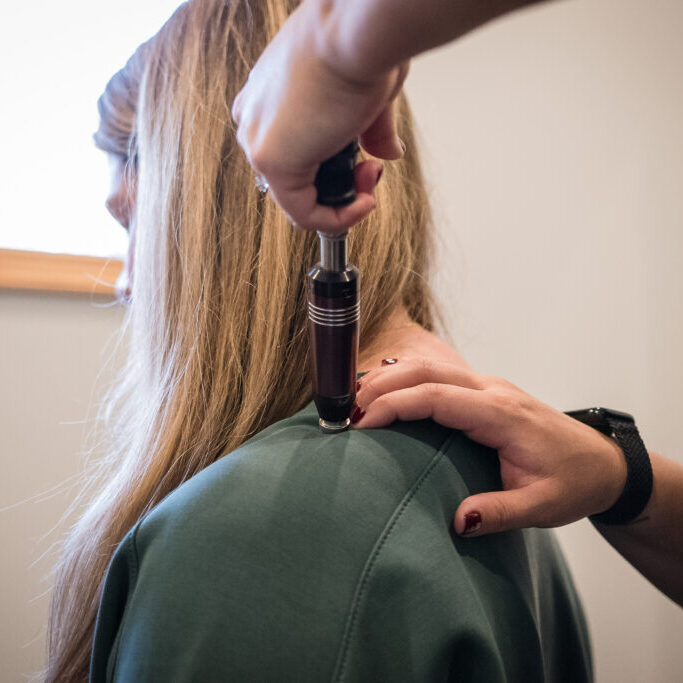 Activator Technique adjustment on patient's shoulder at Skelly Chiropractic