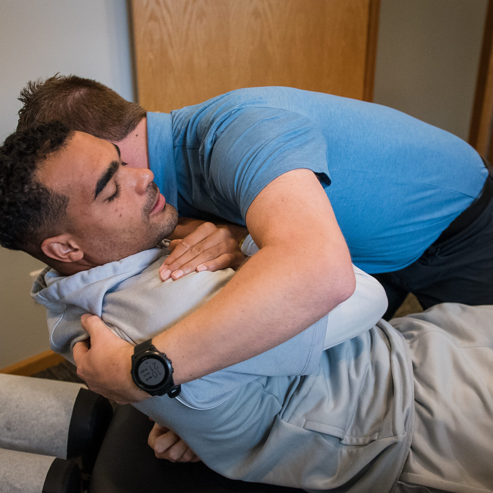 Chiropractor performing Diversified Technique adjustment on patient's back