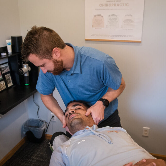 Chiropractor performing neck adjustment on patient