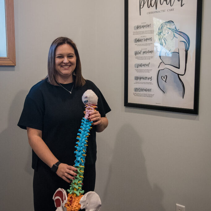 Dr. Kacey Skelly holding spine model for Webster Technique and pregnancy chiropractic care.